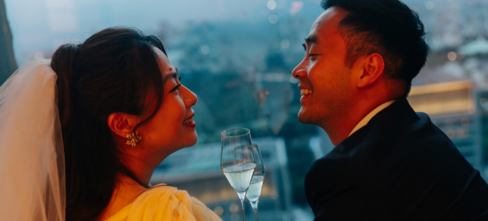 Kristel and Delong toasting with champagne above the city at dusk
